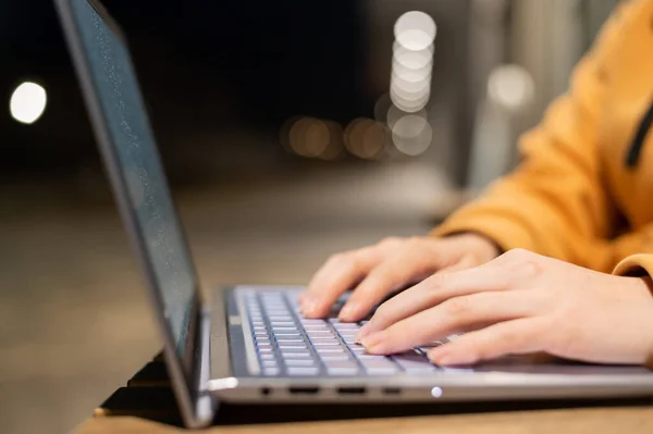 Closeup of female hands on a computer touchpad. Freelancer remotely works on a laptop in the fresh air. A woman is studying on the street in the evening. — Stock Photo, Image