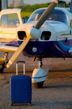 Mavi bir bavul ve küçük özel bir jet indi. Hava taksisi için pervaneli dört koltuklu bir uçak. Seyahat konsepti. VIP kişiler için uçak.