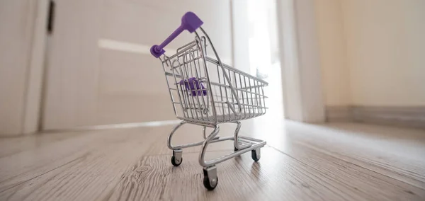 Grocery cart at the open door. Delivery of products. Mini trolley for contactless delivery.