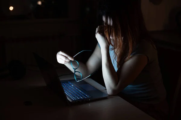 Fatiguée femme rousse travaillant sur un ordinateur portable. La fille à l'ordinateur dans le désespoir tient la main sur le pont du nez. Échec au travail. Date limite et heures supplémentaires . — Photo