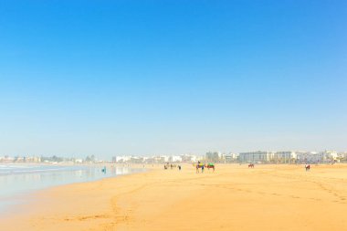 ESSAOUIRA / MOROCCO - 13 HAZİRAN 2020: İnsanlar güneşli kış günlerinde güzel geniş Essaouira Sahili boyunca yürürler 