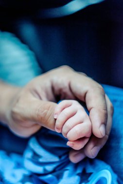 Bebek bacaklarını elleri ile tutar
