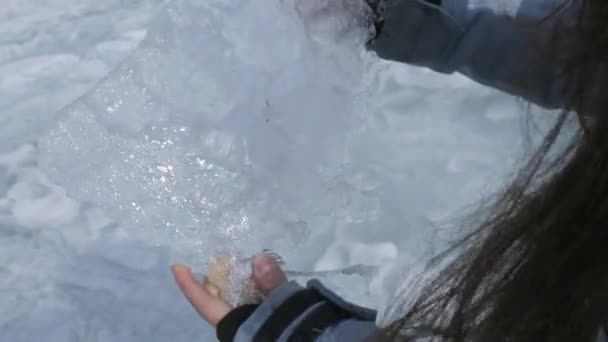 Femeia ține gheața de cauciuc în mâini și o mișcă, făcându-o să strălucească la soare. . — Videoclip de stoc