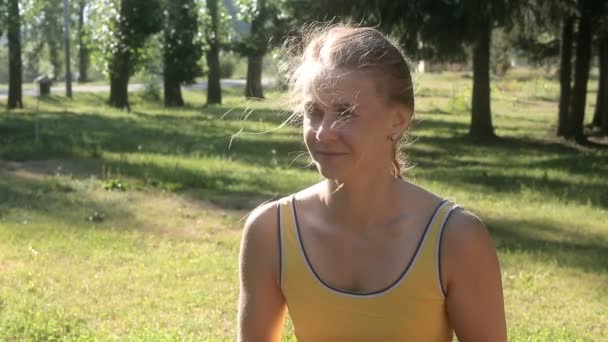 Vrouw in een sport shirt met relish drinken uit een beker in het park. — Stockvideo