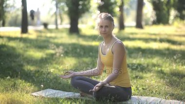 Lotus pozisyonu gözleri açık otururken ve Parkı'nda gülümseyen kadın