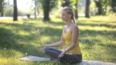 Çekici kadın açık havada yaz sabahı oturan yoga uygulamak.