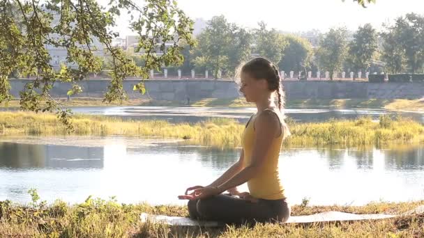 Vrouw met ogen gesloten praktizerende yoga op de achtergrond van de stad. — Stockvideo