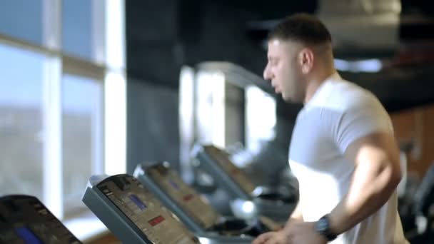 Young man is running on treadmill in sports club. — Stock Video