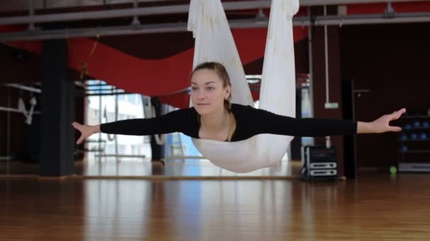 Kvinna gungor i en luft hängmatta ovanför golvet under flyga yoga. — Stockvideo