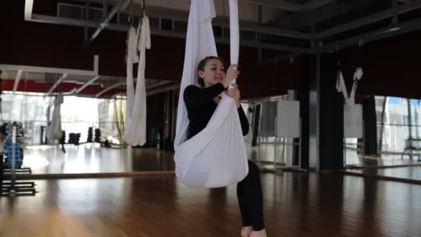 Junge Dame sitzt auf weißer Hängematte im Fliegenyoga-Studio. — Stockvideo