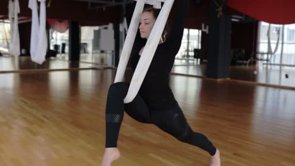 Dans la femme de gymnase étire ses jambes sur l'hamac au-dessus du plancher . — Video