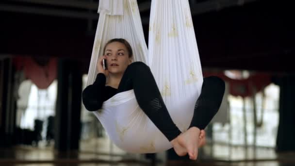 Sportlerin telefoniert während einer Ruhepause im Fliegenyoga-Kurs. — Stockvideo