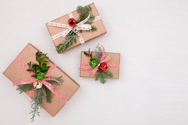 Kerstcompositie. Kerst geschenkdozen versierd dennenboom takken en klokken op witte achtergrond — Stockfoto