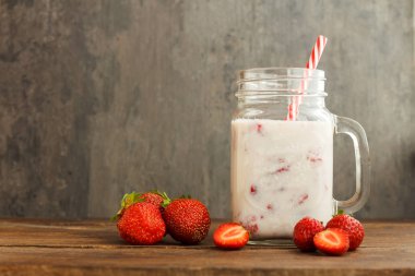 Çilek güler yüzlü veya milkshake rustik siyah arka plan üzerine kavanoz içinde