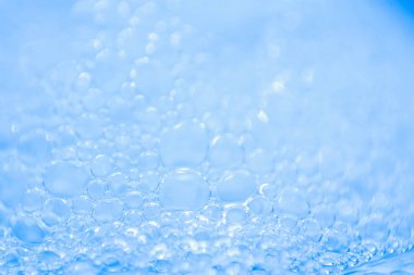 Makro görünümü sabunlu beyaz köpük kabarcıklar. sabun köpüğü ve duş doku. Mavi arka plan. yumuşak odak