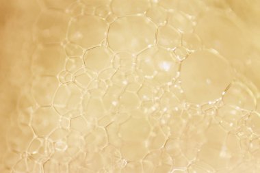 Makro görünümü altın sabunlu köpük kabarcıklar. sabun köpüğü ve duş doku. Mavi arka plan. yumuşak odak