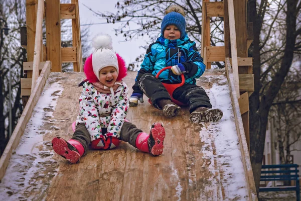 Boy and girl ride a hill in winter — Stock Photo, Image