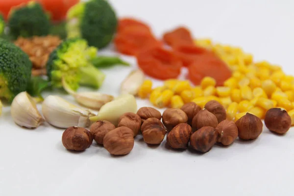 Gesunde Ernährung. Möhren, getrocknete Aprikosen, Knoblauch, Brokkoli, Nüsse, Haselnüsse. Essen auf weißem Hintergrund — Stockfoto
