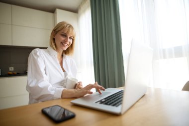 Güzel hamile iş kadını ve evde çalışırken gülümsüyor.