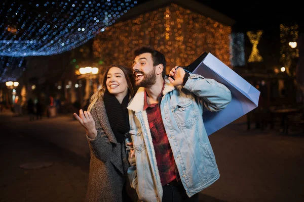 Primer plano de una joven pareja de compras en la ciudad por la noche — Foto de Stock