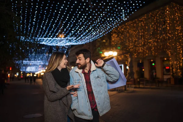 Primer plano de una joven pareja de compras en la ciudad por la noche — Foto de Stock