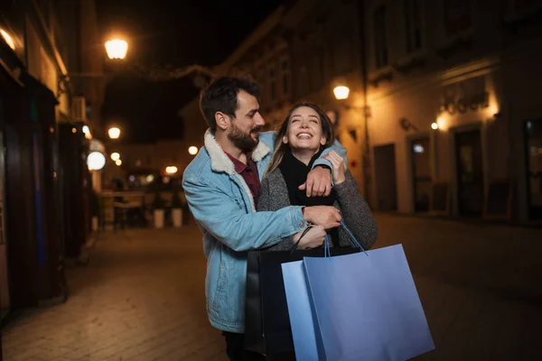 Primer plano de una joven pareja de compras en la ciudad por la noche — Foto de Stock