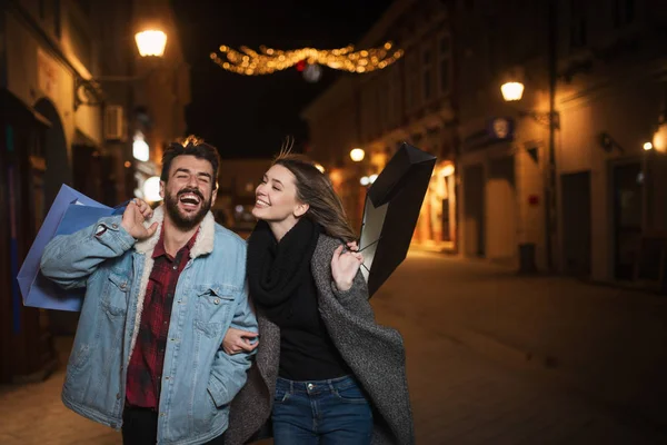 Primer plano de una joven pareja de compras en la ciudad por la noche — Foto de Stock