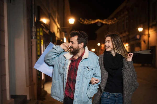 Primer plano de una joven pareja de compras en la ciudad por la noche —  Fotos de Stock