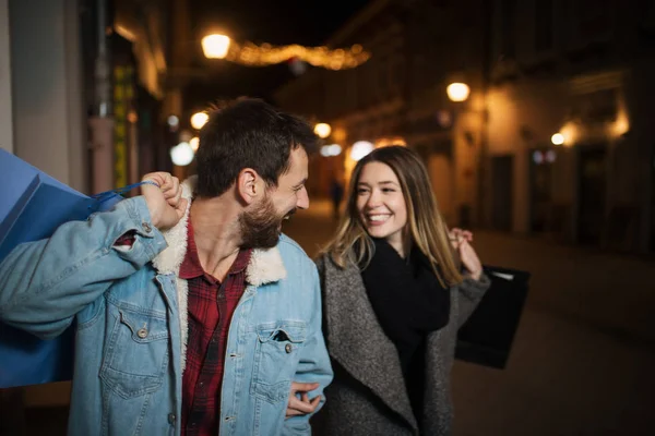 Geceleri şehirde alışveriş yapan genç bir çiftin fotoğrafını çek. — Stok fotoğraf
