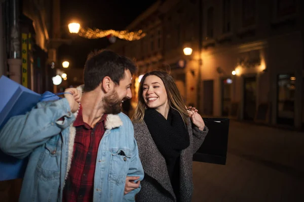 Close up of a young couple shopping in the city at night — Stock Photo, Image