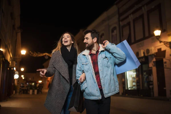 Close up of a young couple shopping in the city at night — Stock Photo, Image