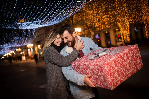 Regalo de Navidad, feliz pareja con regalo de Navidad y Año Nuevo en la calle — Foto de Stock