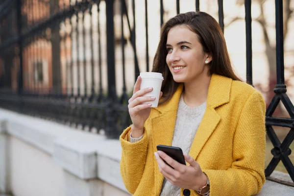 Mujer sonriente usando móvil y bebiendo café — Foto de Stock