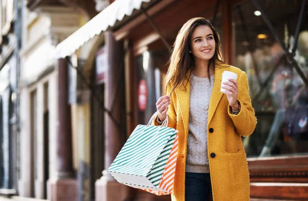 Retrato de una hermosa mujer con bolsas de compras y beber café — Foto de Stock