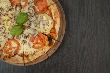 Tahta masada domatesli, peynirli ve mantarlı taze pizza.