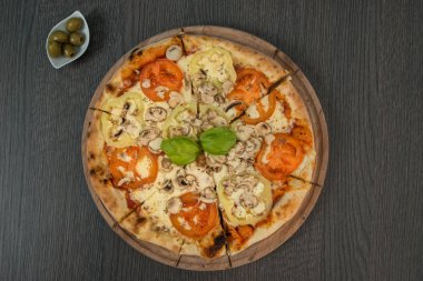 Tahta masada domatesli, peynirli ve mantarlı taze pizza.