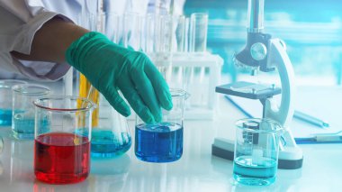 Laboratuvarda deney tüplerindeki renkli sıvıyla çalışan bir araştırmacı. Bilim, teknoloji, sağlık ve tıp konsepti.