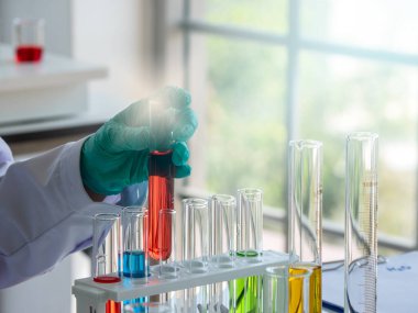 Laboratuvarda incelenmek üzere bilim adamının elinde kırmızı renkli sıvıyla test tüpü bulunuyor. Bilim, tıp ve teknoloji kavramı.