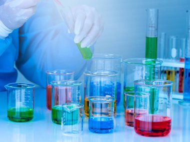 Laboratuvarda deney tüplerindeki renkli sıvıyla işi yapan bir araştırmacı. Sağlık, tıp, bilim ve teknoloji kavramı.