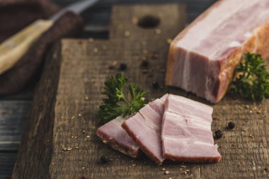 Tütsülenmiş et, dilimlenmiş domuz filetosu ve taze otlar.