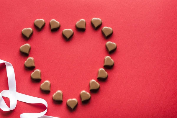 Heart shaped chocolates on red background for Valentine's day — Stock Photo, Image