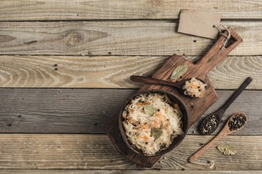 Hindistan cevizi tabağında mayalanmış lahana. Tahtanın üzerinde, açık ahşap bir zeminde. Üst Manzara. Kopyalama. Yatay oryantasyon. Düz yatıyordu.