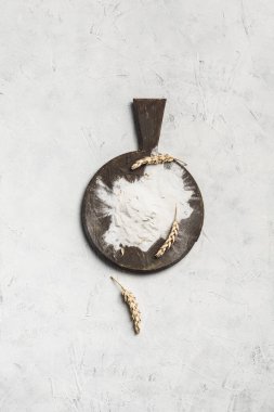 Açık arkaplanlı un ve buğday dikenli yuvarlak kahverengi tahta. Kopyalama alanı ile üst görünüm. düşey yönelim