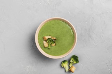 Açık gri arka planda kızarmış ekmekli brokoli kremalı çorba. Sağlıklı beslenme kavramı. Kopyalama alanı olan üst görünüm. Yatay yönelim.