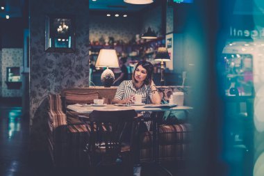 Kafenin içinde elinde bir fincan kahveyle bir kızın portresi. Bir kafede Sabah Kahvaltısı. Kopya alanı ile yatay yönelim.