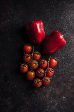 Taze bahar biberleri ve koyu arkaplanda kiraz domatesleri. Fotokopi alanı olan üst görünüm. Sağlıklı beslenme için sebzeler. Dikey yönelim.