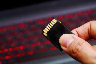 Bellek kartı laptop klavye arka planda tutan el