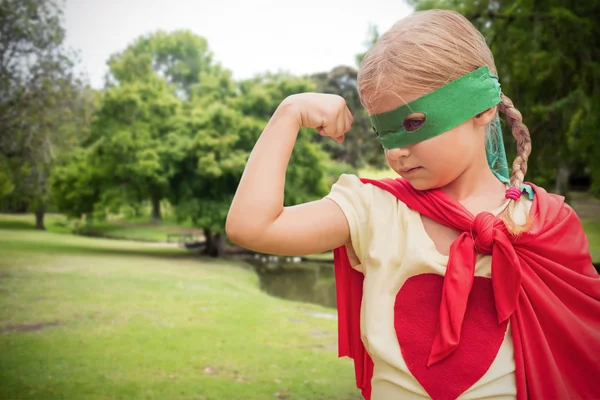 Girl in red cape showing muscles — Stock Photo, Image