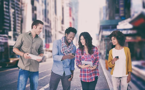 Amigos mirando la tableta y sosteniendo teléfonos — Foto de Stock