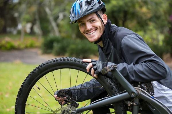 Ciclista masculino reparando sua bicicleta de montanha — Fotografia de Stock